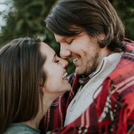 Couple snuggling up together in the cold in a plaid blanket | Date Your Spouse