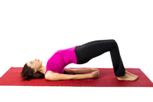 A woman enjoying her time working out at home - dateyourspouse.com Wife practicing the lying gluteal bridge on a yoga mat for Sexercise date | The Dating Divas