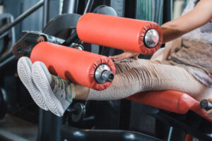 A wife working out with spouse for date night - dateyourspouse.com A woman doing seated leg extensions for her leg workout | The Dating Divas