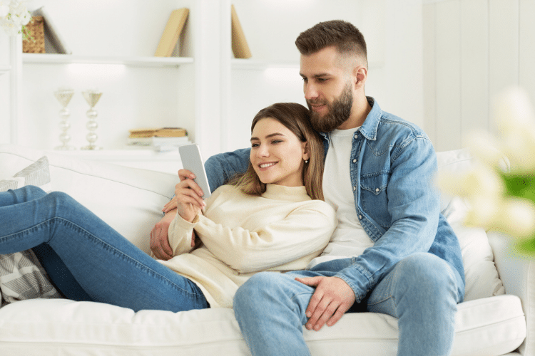 Couple snuggling and smiling together on couch | Date Your Spouse