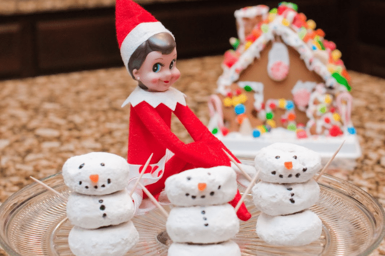 Elf on the shelf sits by snowmen made out of mini donuts | The Dating Divas