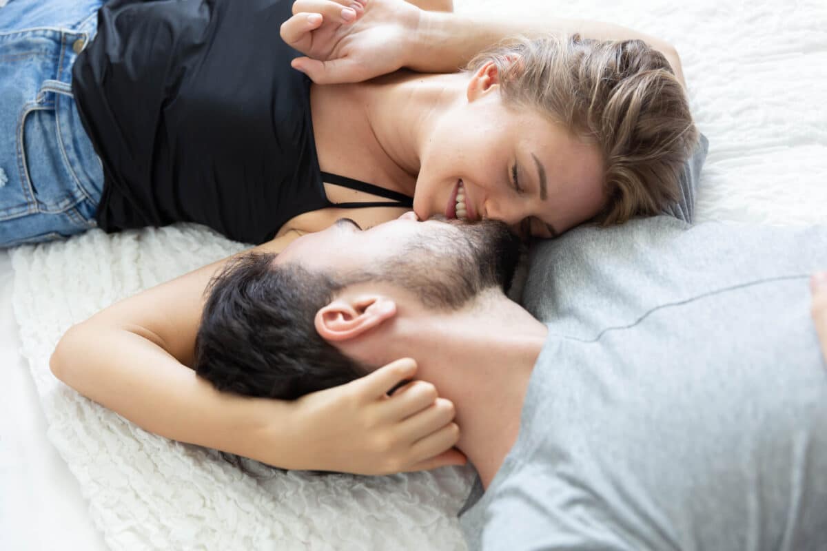 A man and woman working on increasing libido while laying in bed together | The Dating Divas