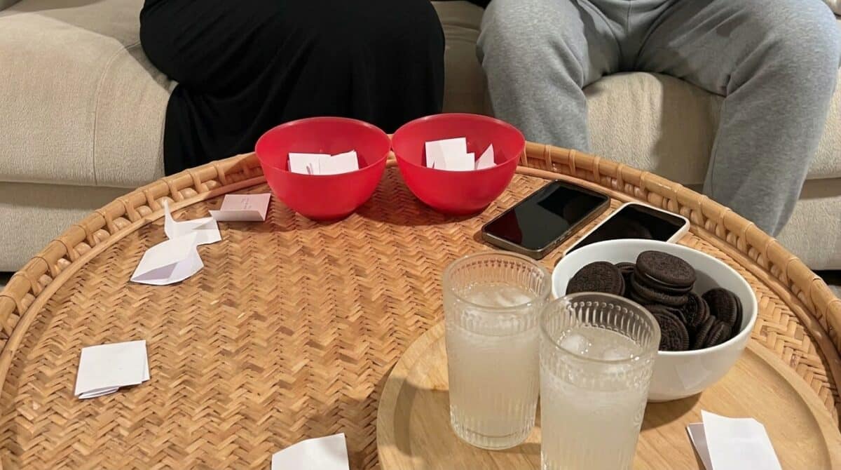 Two bowls with slips of paper, two cell phones, two drinks, and a bowl of snacks for the Memory Lane Game for date night